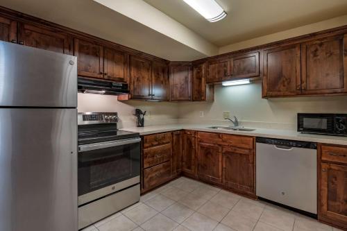 a kitchen with wooden cabinets and a white refrigerator at Best Western Desert Inn in West Yellowstone
