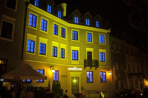 a yellow building with people standing outside of it at night at Hotel Alter in Lublin