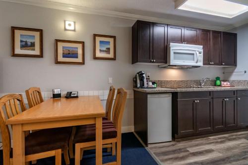 a kitchen with a wooden table and a kitchen with a microwave at Best Western Inn at Penticton in Penticton