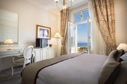 una camera da letto con un letto, una scrivania e una finestra di Hotel Kvarner - Liburnia a Opatija
