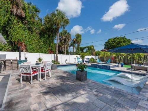 a patio with a table and chairs next to a swimming pool at Sanctuary Home Naples-Private Pool and Lanai! in Naples