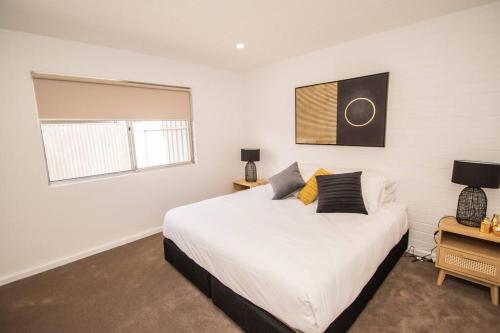 sypialnia z dużym białym łóżkiem i oknem w obiekcie Willow Court Unit 3 w mieście Broken Hill