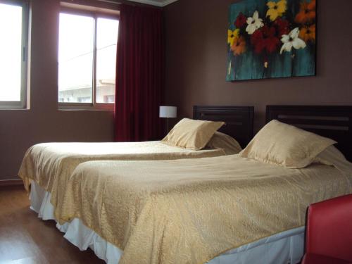 1 dormitorio con 2 camas y un cuadro en la pared en Apart Hotel Cancura, en Chillán