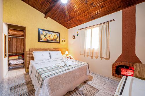 a bedroom with a bed and a fireplace at Pousada Villa Da Montanha in São Bento do Sapucaí