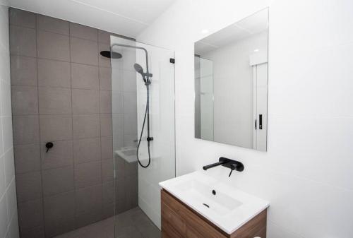 uma casa de banho branca com um chuveiro e um lavatório. em Willow Court Unit 4 em Broken Hill