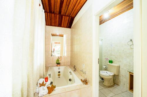 a bathroom with a bath tub and a toilet at Pousada Villa Da Montanha in São Bento do Sapucaí