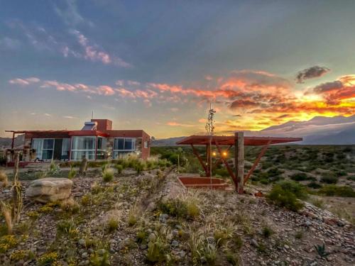 a house in the middle of a field with a sunset at Potre casas de montaña in Potrerillos