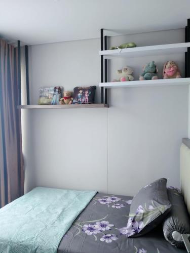 a bedroom with a bed and shelves with stuffed animals at Palam Mansion at Apartment One Residence in Batam Center
