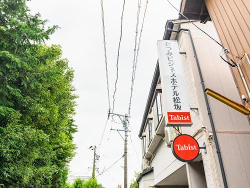 una señal para un hotel al lado de un edificio en Tabist Tatsumi Business Hotel Matsusaka, en Matsusaka