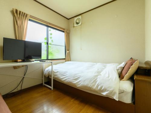 a bedroom with a bed and a tv and a window at Tabist Tatsumi Business Hotel Matsusaka in Matsuzaka