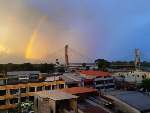 a rainbow over a city with a bridge at Hostal R. Williams in Puerto Francisco de Orellana