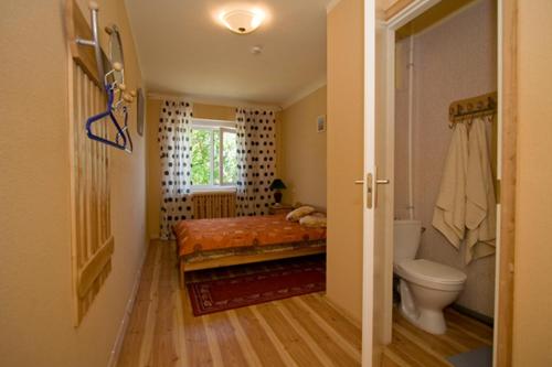 a bedroom with a bed and a toilet and a window at Motelis Aldari in Pastende