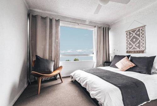 a bedroom with a bed and a window and a chair at Bay Properties Pacific Sun in Yamba