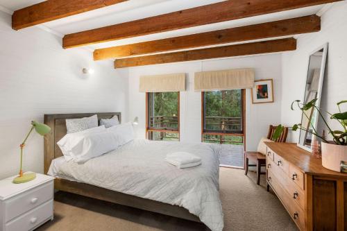 een slaapkamer met een bed, een bureau en ramen bij Fern Cottage in Wye River
