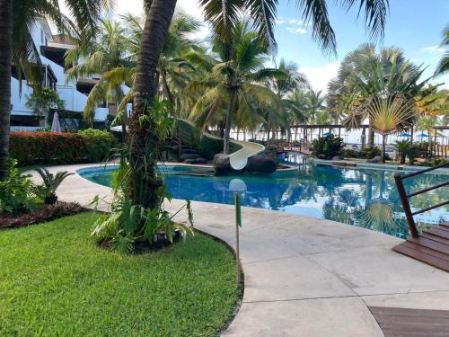ein Pool mit Palmen und ein Resort in der Unterkunft Apartamentos Los Cabos Monterrico by l´Aurora Inn in Taxisco