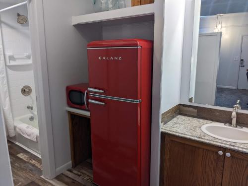 um antigo frigorífico vermelho numa casa de banho com lavatório em The Oakwood Inn em Sterling