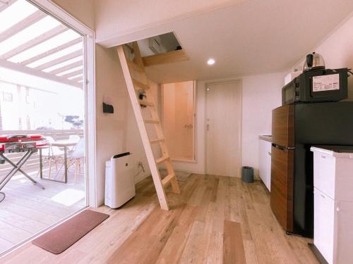 Habitación pequeña con cocina con nevera y escalera. en Necoana Glamping富士山景BBQトレーラーヴィラ en Fujikawaguchiko