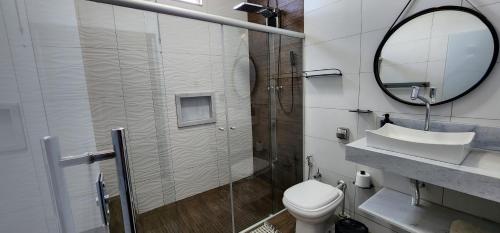 a bathroom with a shower and a toilet and a mirror at Pousada Lago Azul in Delfinópolis