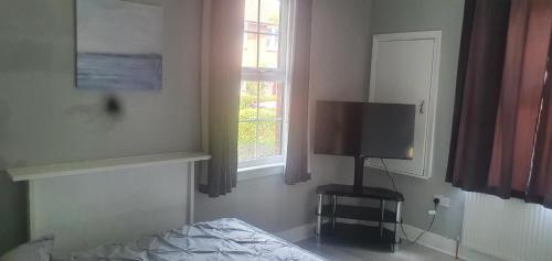 a bedroom with a bed and a tv and a window at Tower Gardens Residence in London