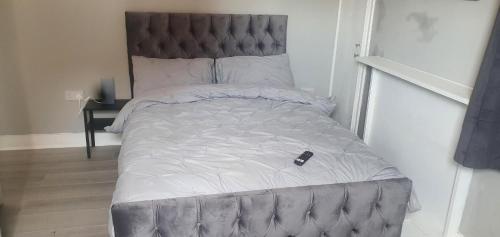 a bed with a remote control sitting on top of it at Tower Gardens Residence in London