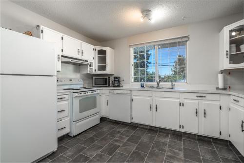 a white kitchen with white appliances and a window at H-Home by Deerfoot city in Calgary