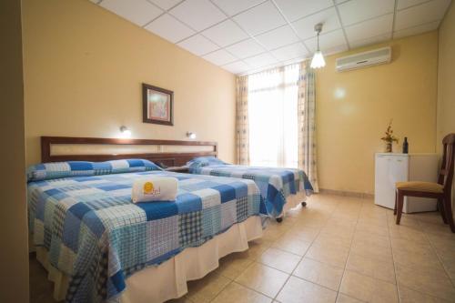 a hotel room with two beds and a chair at Hotel del Sol in Tarija