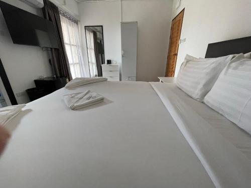 a large white bed with two white towels on it at Laewan Guesthouse in Baan Tai
