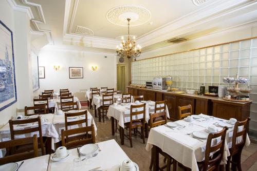 a restaurant with white tables and chairs and a bar at Hotel Dom Sancho I in Lisbon
