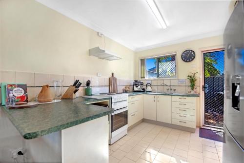une cuisine avec des placards blancs et un comptoir dans l'établissement Park Beach Retreat, à Coffs Harbour