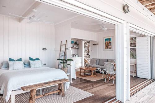 a bedroom with a bed and a patio with a table at Bay Properties Beach House Studio in Yamba