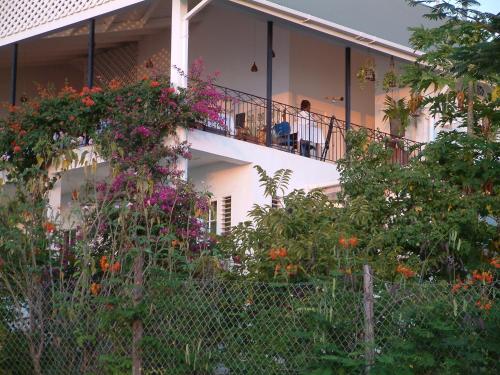 a woman sitting on the balcony of a house with flowers at Green Roof Inn in Carriacou