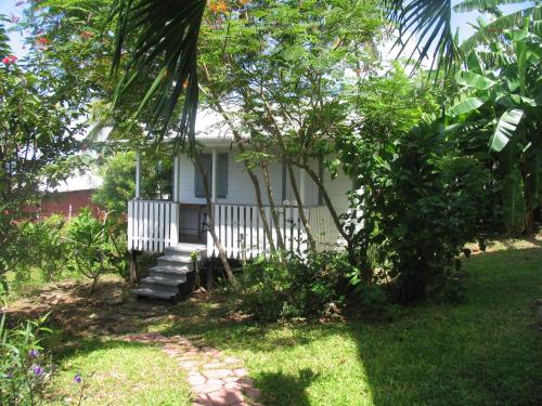 a small white house with stairs in a yard at Green Roof Inn in Carriacou