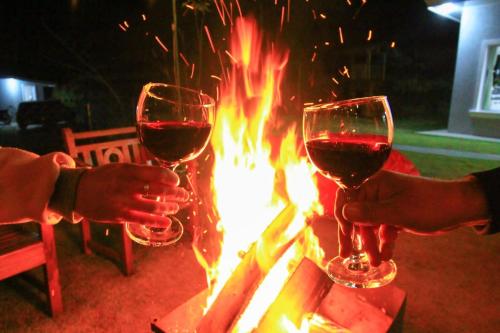 two people holding wine glasses next to a fire at Aconchego Véu da Noiva in Campos do Jordão