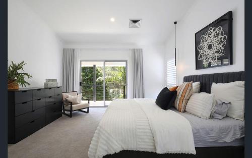 a bedroom with a large bed and a window at Central Coast - Luxurious Beach House 400m to Beach in Bateau Bay