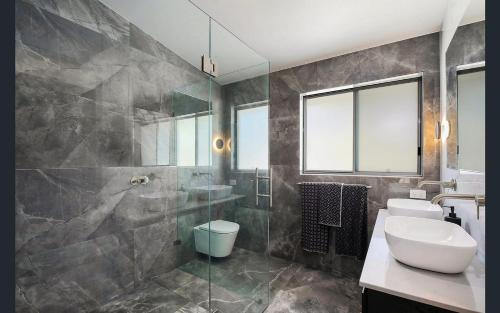 a bathroom with a sink and a toilet and a shower at Central Coast - Luxurious Beach House 400m to Beach in Bateau Bay