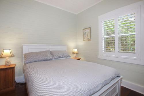 a white bedroom with a bed and two lamps at Sunroom Cottage in Tea Gardens