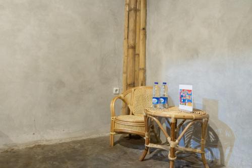a wicker chair and a table with bottles on it at Urbanview Ta-ke Residence Blok M by RedDoorz in Jakarta
