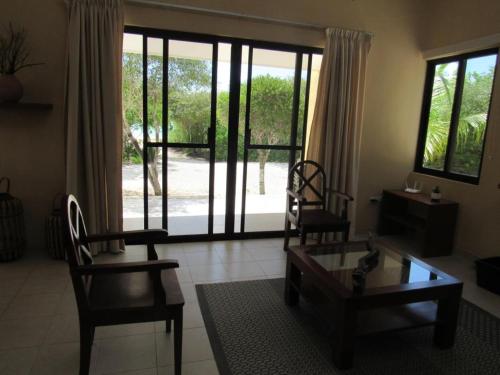 a living room with two chairs and a table and a glass door at Two bedroom beachfront villa Celestun in Celestún