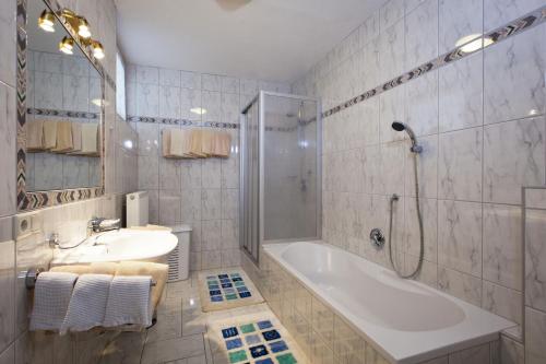 y baño con bañera, lavamanos y ducha. en Appartements Kristall, en Nauders