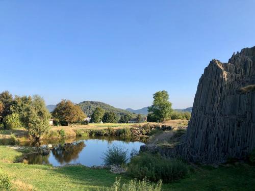 a pond in a field next to a stone wall at Apartmán V Krátké in Stein Schönau