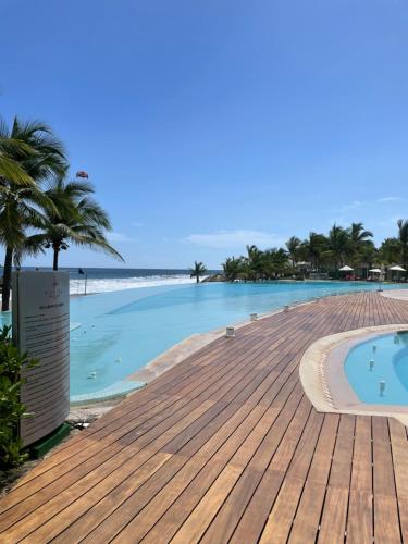 a swimming pool on the beach with a wooden deck at Bay View Grand Marina Ixtapa condo en pie de playa in Ixtapa