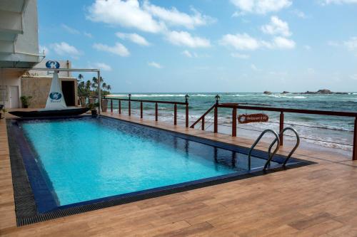 a swimming pool with the ocean in the background at Coral Rock by Bansei in Hikkaduwa