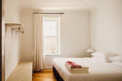 a white bedroom with two beds and a window at Miss Midgley's - Locker Room in Brisbane