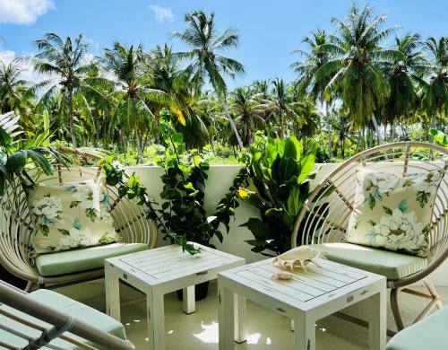 2 Stühle und Tische auf einer Terrasse mit Palmen in der Unterkunft Fairytale Inn in Thoddoo-Atoll