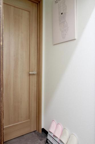 a hallway with a door and pink slippers on the floor at Hachiken Chaya 2F 1-6ppl in Sapporo