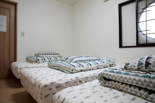 three beds in a room with pillows on them at Hachiken Chaya 2F 1-6ppl in Sapporo