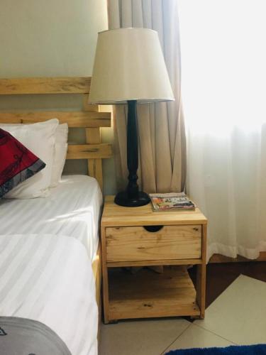 a lamp on a night stand next to a bed at The Greenville Home in Mbarara