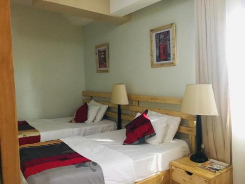 two beds in a hotel room with two lamps at The Greenville Home in Mbarara