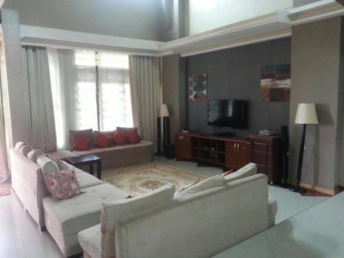 ein Wohnzimmer mit 2 Sofas und einem TV in der Unterkunft The Greenville Home in Mbarara
