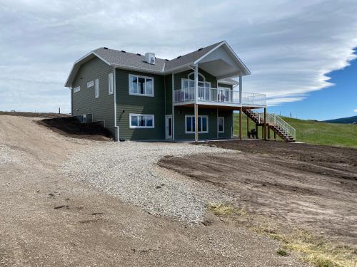 a house sitting on top of a dirt road at Thistle Ridge (Upper) New Waterton Lakes Area Waterfront Home in Mountain View